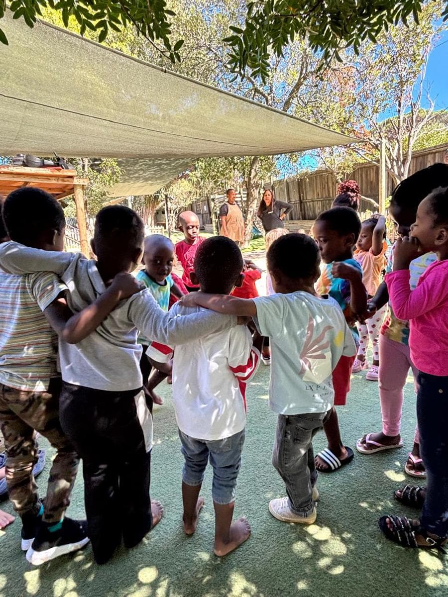 A joyful group of children sharing a big hug outdoors