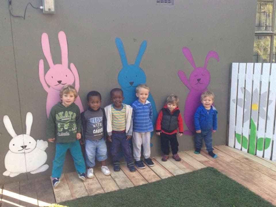 Children standing proudly beside the painted bunny mural
