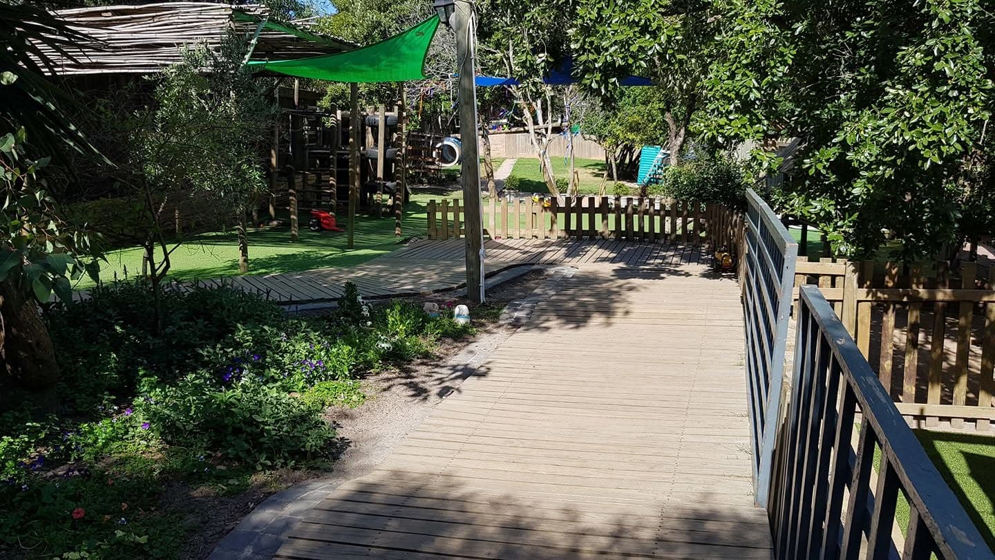 The wooden boardwalk winding through the leafy garden