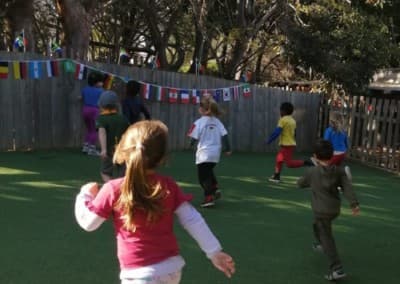 Children running together in the garden beneath international flag bunting