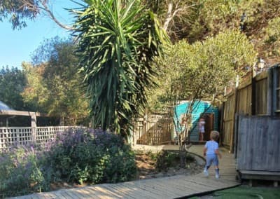 A toddler exploring the wooden garden pathway among the plants
