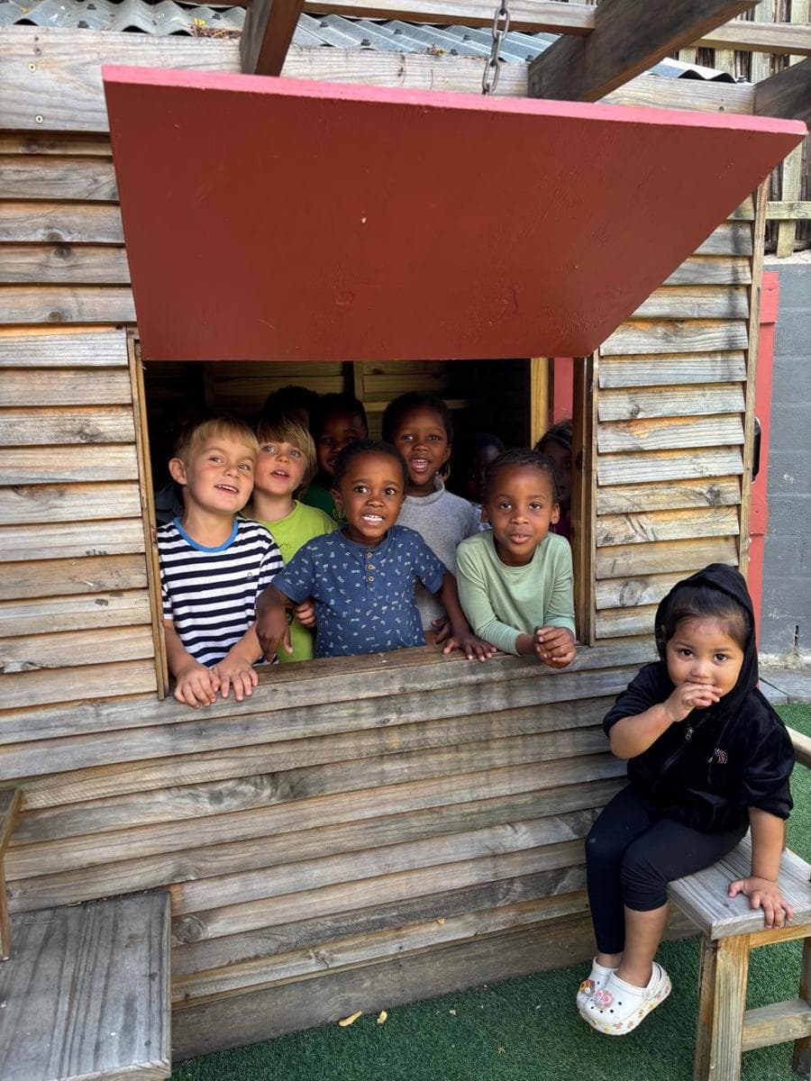 Children waving from the window of the wooden play fort